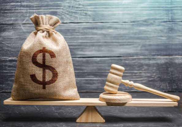 istockphoto-1133882253-612x612 Bag of money with a dollar sign and a judge's hammer on the scales. Concept lobbying for the adoption of a law or a norms, corruption. Payment of fines and penalties. award of compensation for damage